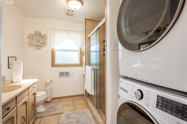 laundry area featuring light tile patterned flooring, stacked washer / drying machine, sink, and a textured ceiling