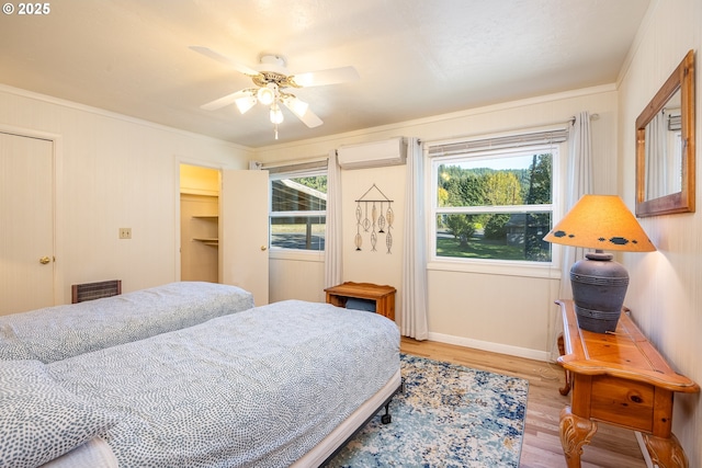 bedroom featuring crown molding, ceiling fan, a wall mounted air conditioner, and wood-type flooring