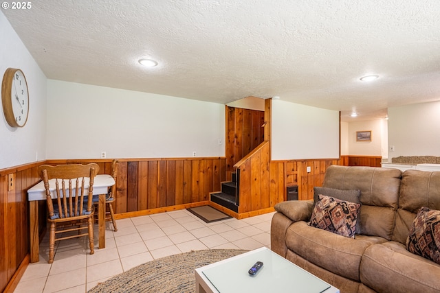 living room featuring light tile patterned floors, a textured ceiling, and wood walls