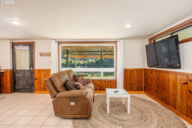 tiled living room featuring a textured ceiling and wood walls