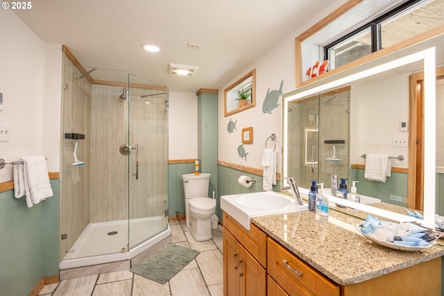 bathroom with vanity, a textured ceiling, a shower with door, and toilet