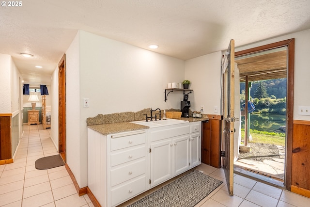 kitchen with white cabinetry, light tile patterned flooring, sink, and a textured ceiling