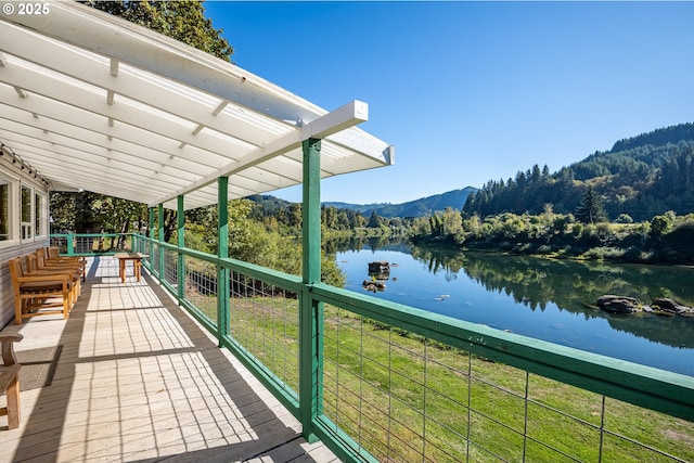 wooden deck with a water and mountain view