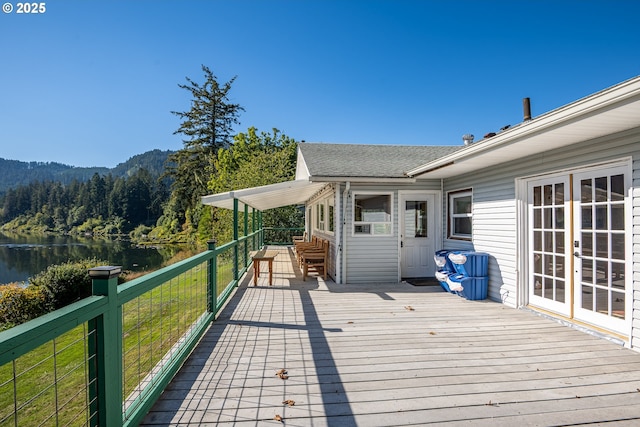 wooden terrace with a water and mountain view and french doors