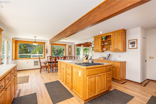 kitchen with pendant lighting, a kitchen island with sink, beam ceiling, black gas cooktop, and light hardwood / wood-style floors