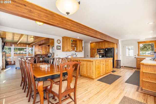 dining room featuring beamed ceiling, sink, and light hardwood / wood-style floors