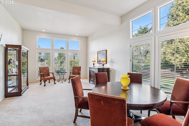 dining space featuring light carpet, a high ceiling, and baseboards