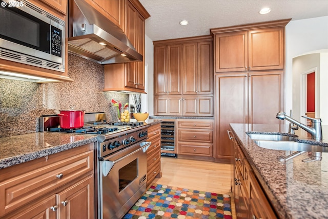 kitchen with arched walkways, decorative backsplash, stainless steel appliances, a sink, and exhaust hood