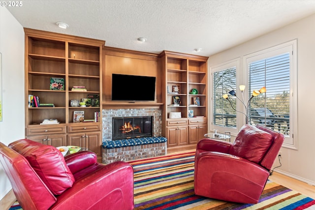 living area with a fireplace, baseboards, and a textured ceiling