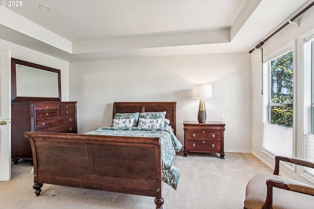 bedroom featuring a tray ceiling, carpet flooring, and baseboards