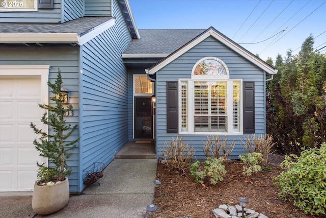 entrance to property with an attached garage and roof with shingles