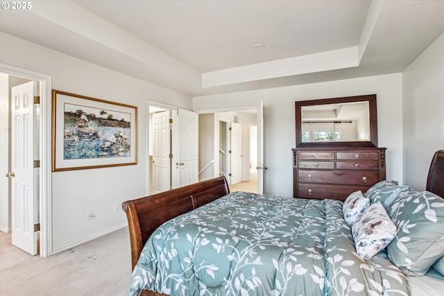 bedroom featuring a raised ceiling, light colored carpet, and baseboards