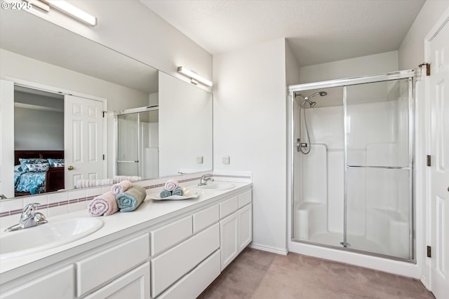 ensuite bathroom with double vanity, ensuite bath, a sink, and a shower stall