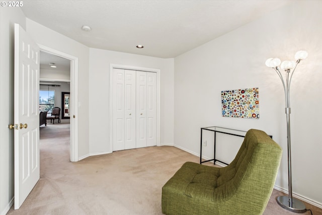 sitting room featuring carpet flooring and baseboards