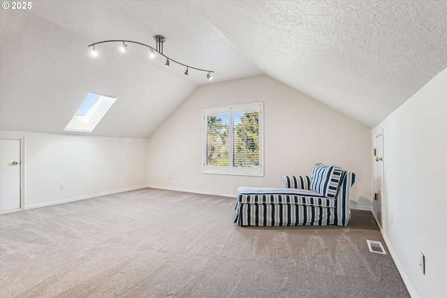 bonus room featuring a textured ceiling, vaulted ceiling with skylight, carpet floors, visible vents, and baseboards