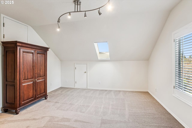 bonus room with lofted ceiling with skylight, baseboards, and light colored carpet