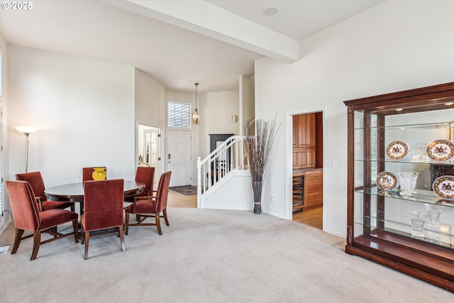 carpeted dining space featuring stairs, wine cooler, beamed ceiling, and baseboards