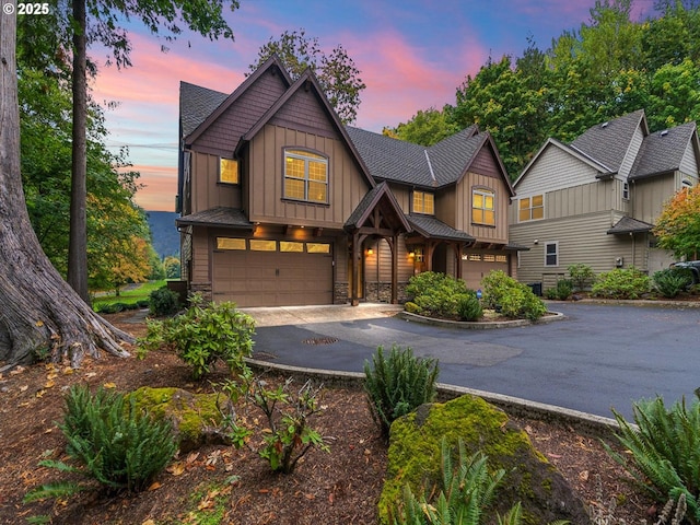 craftsman-style house featuring an attached garage, board and batten siding, driveway, and stone siding