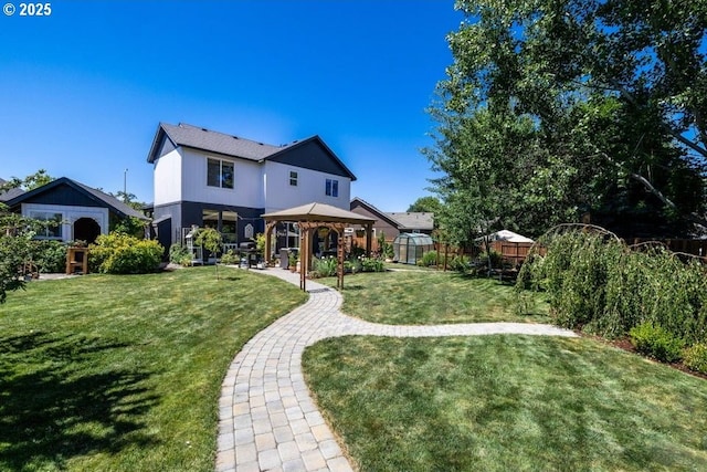 rear view of property with a yard, fence, and a gazebo