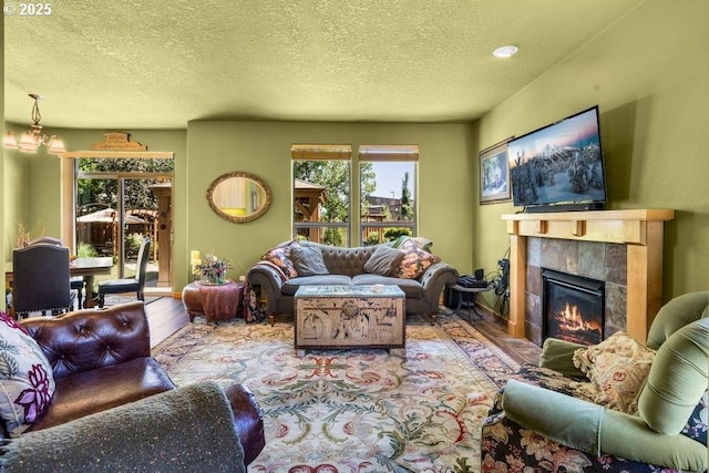 living room featuring a textured ceiling, a tile fireplace, and wood finished floors