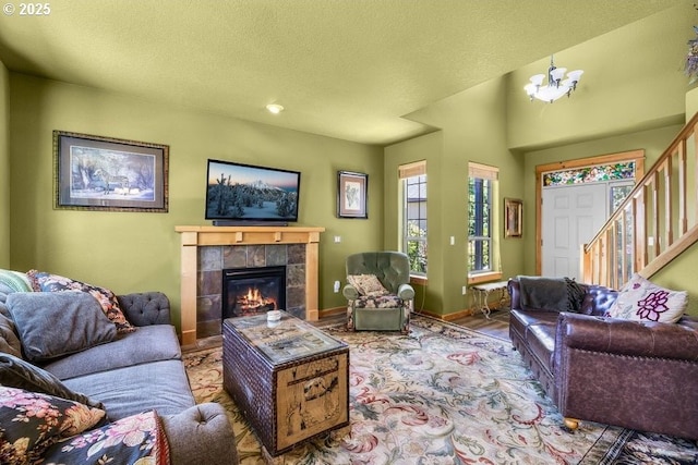 living room with a textured ceiling, stairway, a fireplace, and an inviting chandelier