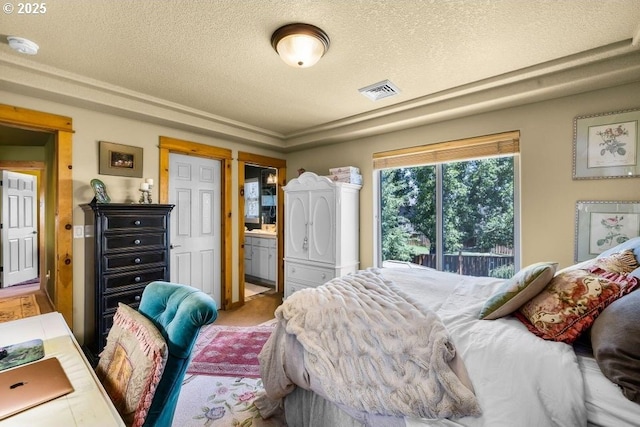 bedroom featuring carpet floors, visible vents, connected bathroom, and a textured ceiling