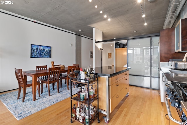 kitchen featuring light wood-type flooring, dark countertops, a center island, and gas stove