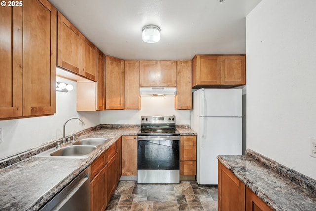 kitchen featuring a sink, brown cabinets, stone finish floor, under cabinet range hood, and appliances with stainless steel finishes