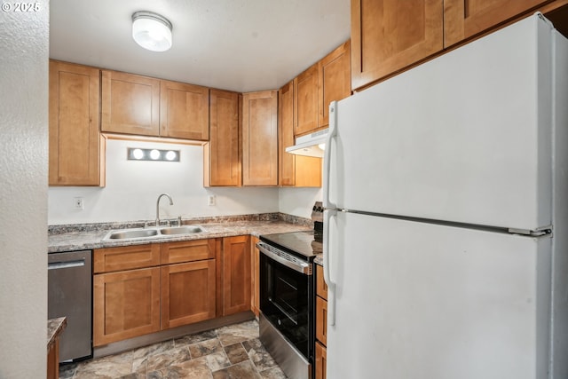 kitchen with a sink, stainless steel appliances, under cabinet range hood, and stone finish flooring