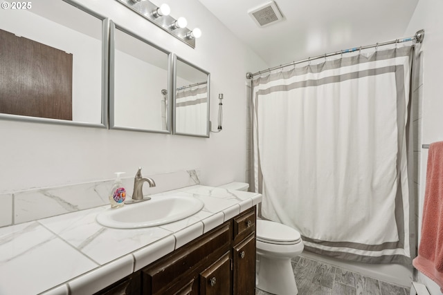 bathroom with shower / bath combo with shower curtain, toilet, visible vents, vanity, and wood finished floors