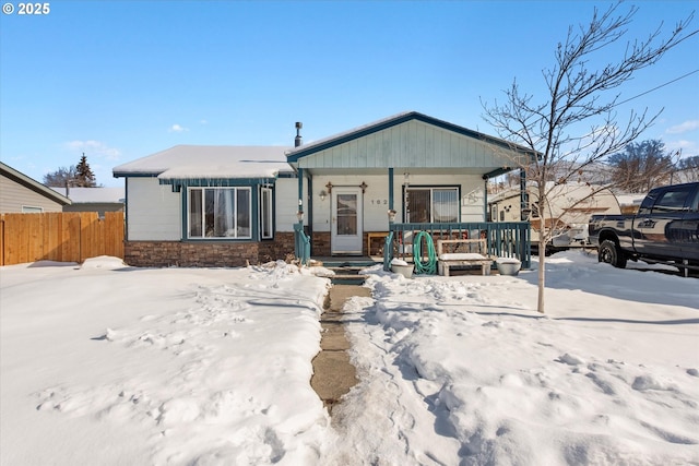 view of front of property featuring stone siding, a porch, and fence