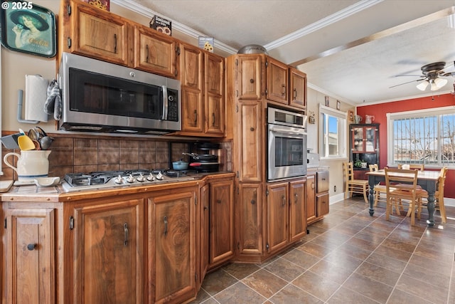 kitchen featuring appliances with stainless steel finishes, tasteful backsplash, a textured ceiling, ceiling fan, and ornamental molding