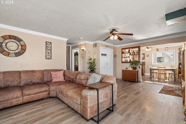 living room with a textured ceiling, ornamental molding, ceiling fan, and light hardwood / wood-style floors