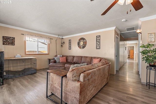 living room with hardwood / wood-style flooring, a textured ceiling, and ornamental molding