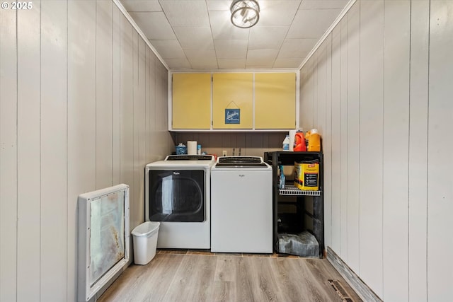 washroom with wooden walls, washing machine and dryer, and light hardwood / wood-style flooring