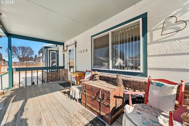 wooden terrace featuring covered porch and fence