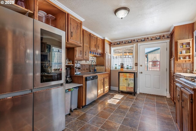 kitchen with a textured ceiling, appliances with stainless steel finishes, sink, and ornamental molding