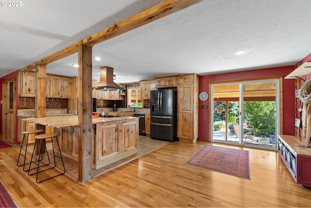 73594 Davis Ln, Pendleton, OR 97801 - kitchen featuring island exhaust hood, black appliances, light wood-style floors, a textured ceiling, and a kitchen bar