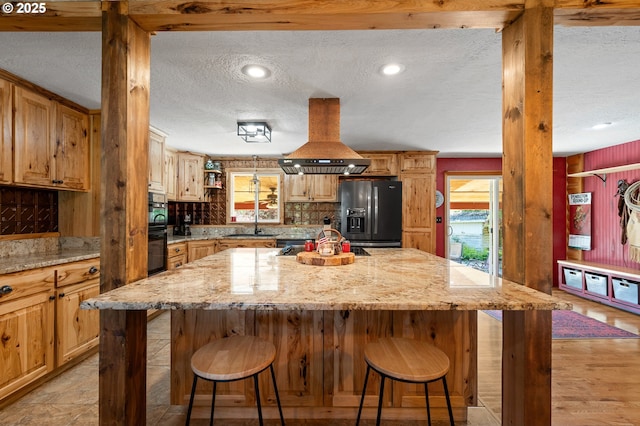 73594 Davis Ln, Pendleton, OR 97801 - kitchen featuring fridge with ice dispenser, island exhaust hood, a textured ceiling, a breakfast bar, and a center island
