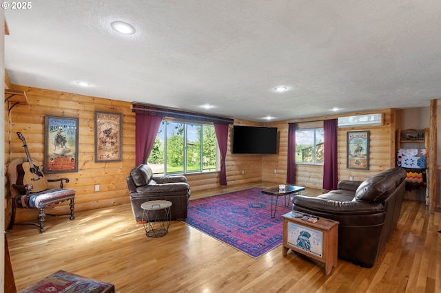 73594 Davis Ln, Pendleton, OR 97801 - living area with log walls, a wall unit AC, a textured ceiling, healthy amount of natural light, and wood finished floors