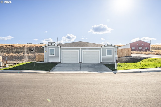 view of front of house featuring driveway, a front lawn, a garage, and fence