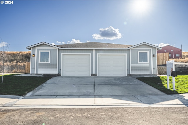 view of front of home with an outbuilding, concrete driveway, a garage, and roof with shingles