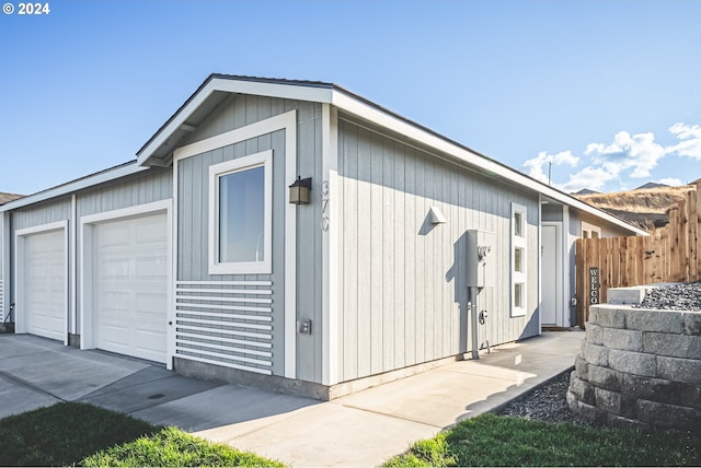 garage featuring concrete driveway and fence