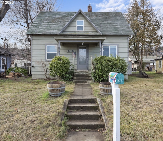 bungalow featuring roof with shingles, a chimney, and a front lawn