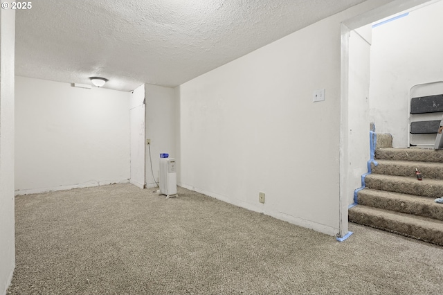 finished basement with a textured ceiling, stairway, and carpet