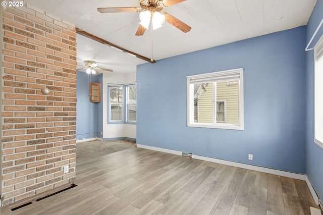 spare room with light wood finished floors, ceiling fan, and baseboards