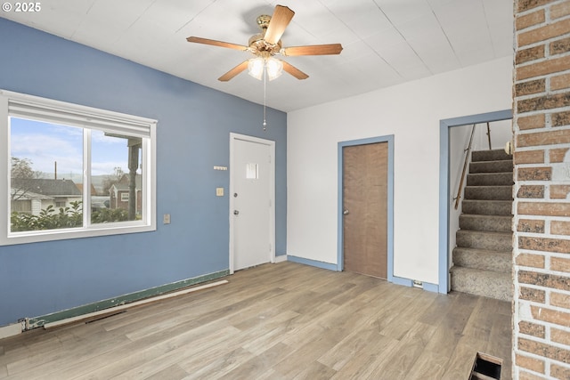 unfurnished room featuring visible vents, a ceiling fan, baseboards, stairway, and light wood finished floors