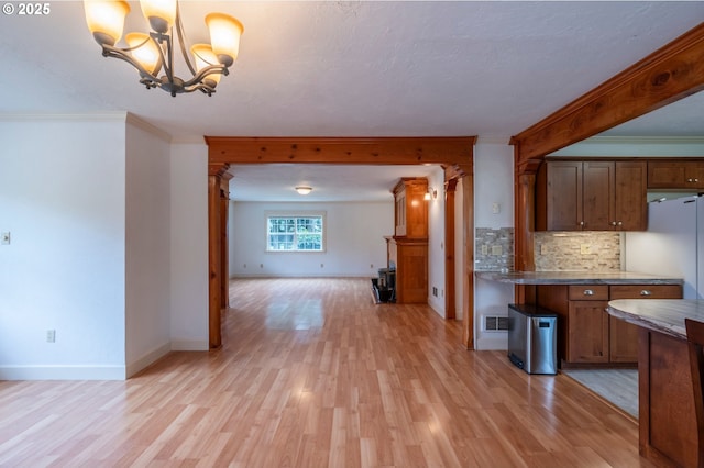 kitchen with ornamental molding, open floor plan, light wood finished floors, and decorative backsplash