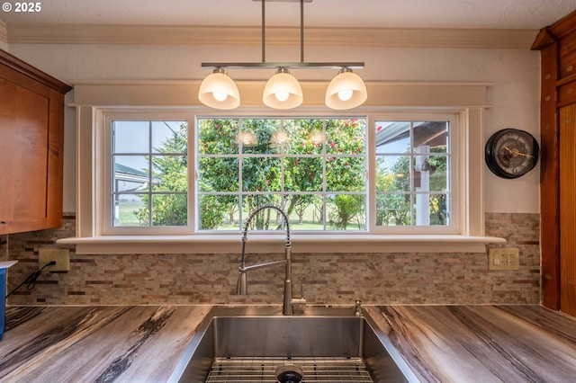 kitchen with brown cabinets, plenty of natural light, a sink, and crown molding