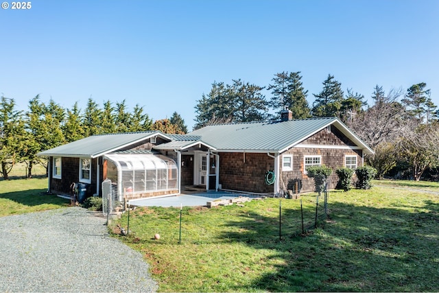 single story home with metal roof, driveway, a chimney, and a front yard